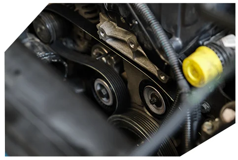 Belts & Hoses03 This is a close-up image of an automotive engine compartment showing serpentine belts, pulleys, and a yellow fluid cap among various mechanical components.