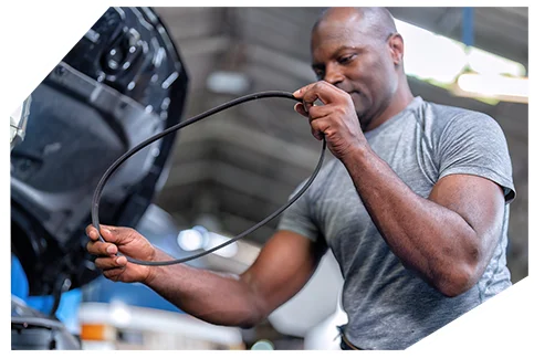 Belts & Hoses05 A person in a gray t-shirt examining a serpentine belt in an auto repair workshop, checking it carefully between their hands.