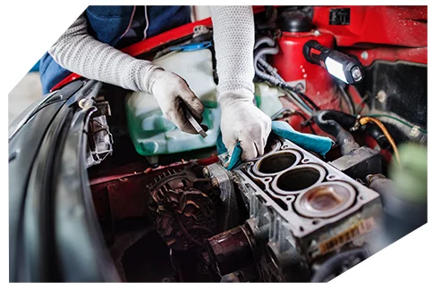 Genaral Automotive 01 A mechanic wearing gloves is repairing a car engine, cleaning the cylinder block with a cloth while holding pliers, surrounded by tools and components.