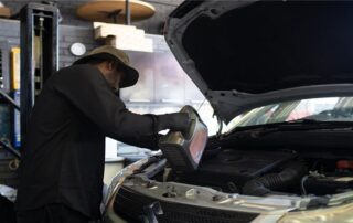Mechanic performing an engine oil change and routine maintenance at Patel Auto.