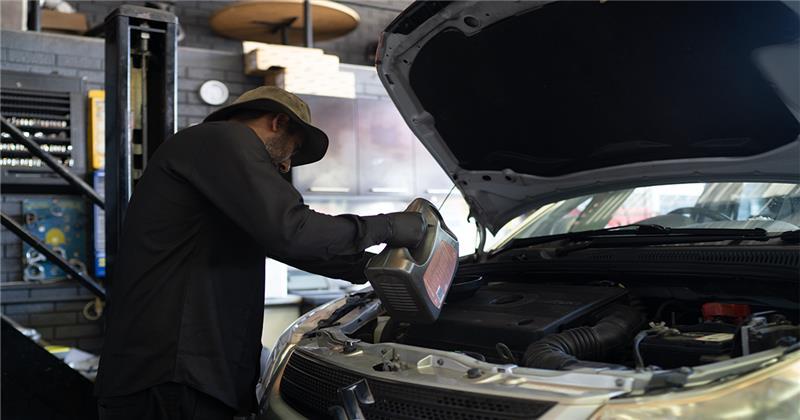 Mechanic performing an engine oil change and routine maintenance at Patel Auto.