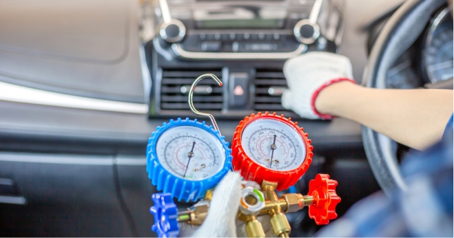 Mechanic checking car air conditioning system with pressure gauges inside a vehicle