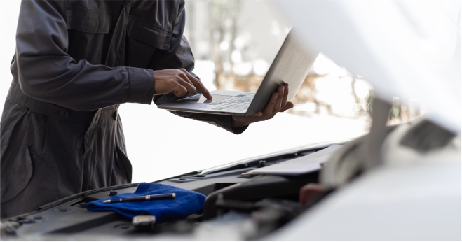 Mechanic using laptop during car servicing regular maintenance saves long-term costs