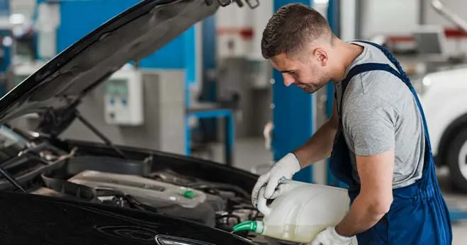 Mechanic pouring fresh oil into a car engine.