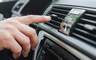 Person adjusting the air conditioning vent inside a modern car dashboard for optimal climate control.