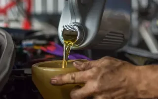 Mechanic pouring engine oil during a car oil change service in an auto workshop