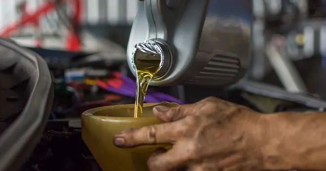 Mechanic pouring engine oil during a car oil change service in an auto workshop