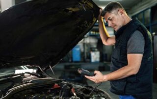 mechanic inspecting car engine with diagnostic tool after check engine light warning
